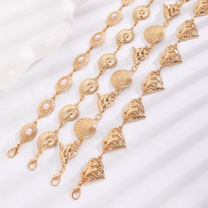 Close-up of golden sea shell and heart pendants on Bohemian style layered waist chains
