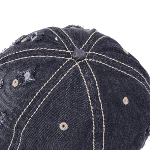 Detail of washed denim baseball cap featuring distressed holes and khaki contrast stitching