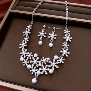 Detail of silver flower pendant necklace and earrings with rhinestones and white pearls
