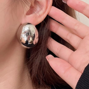 Polished silver minimalist dome earrings with a mirrored finish in a bold oversized style