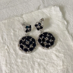 Detail of silver drop earrings with black oval gemstones and sparkling white zircons