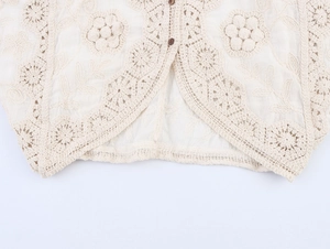 Detail of cream crochet cardigan featuring floral embroidery and brown buttons