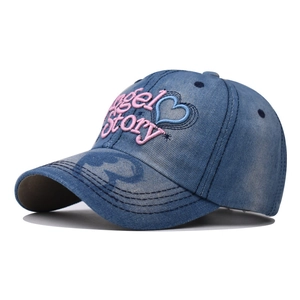 Detail of pink Angel Story embroidery and blue heart on washed blue denim cap