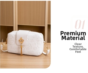 Detail of white mini camera bag with cartoon embossing and gold crown tassel accent