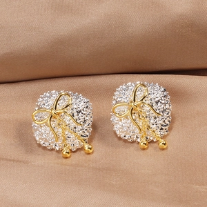 Macro shot of silver textured round earrings with gold bow and bead tassel detail