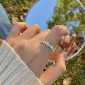 Detail of silver ring with white crystals worn by a model reflected in a mirror outdoors