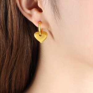 Orecchini a cuore in oro 18K indossati su modella per un look alla moda minimalista