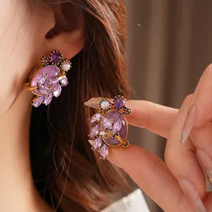 Vintage gold leaf earrings with purple zircon and white pearls shown on a model