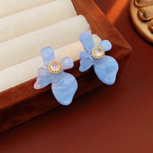 Détail de boucles d'oreilles fleurs en résine bleue avec texture marbrée et zircon