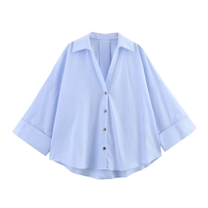 Detail showing the light blue poplin shirt with short wide sleeves and a button-down front