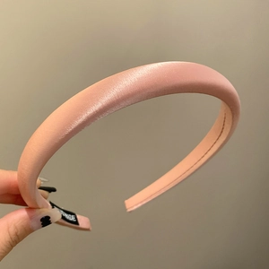 Detailed view of pink satin headband showing the smooth silk texture and inner label