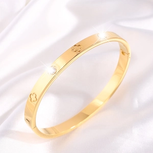 Polished gold titanium steel four-leaf clover bangle with zircon stones on silk background