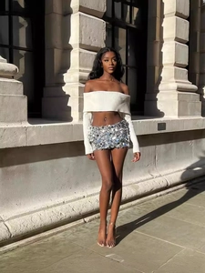 Chic two-piece set featuring white knit crop top and silver sequined mini skirt on model