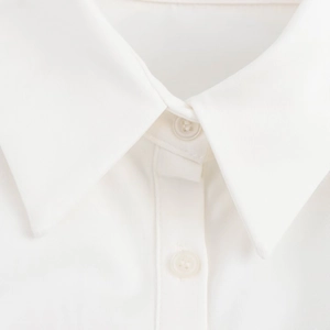 Dettaglio del colletto di una camicia in cotone bianco con trama saia e bottoni in resina
