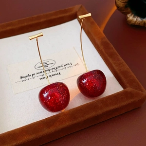 Macro detail of red cherry resin earrings with gold glitter and metallic stems