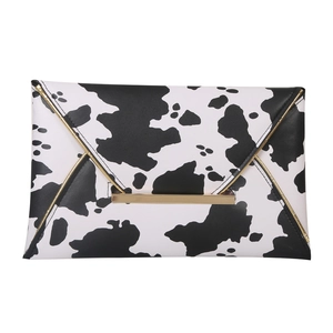 Chic animal print envelope clutch bag with black and white cow patterns and gold metal trim