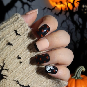 Halloween press-on nails with black heart patterns and cat motifs on pumpkin background