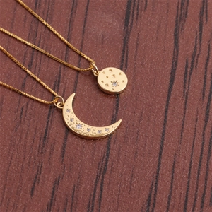 Gold moon and star pendant necklaces with crystals on a dark wood background