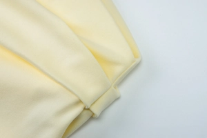 Detail of light yellow dress showing elegant fabric pleats and knotted texture design
