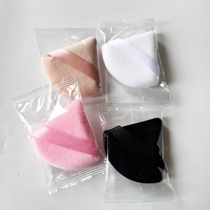 Macro view of four triangular powder puffs in pink, beige, white and black colors