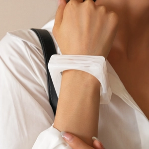 Macro shot of white marble pattern square acrylic bangle worn by a female model