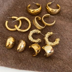 Flat lay of gold plated earring set with ripple textures and geometric shapes on brown felt