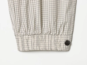 Detailed view of elastic cuff with button on black and white checkered nylon fabric
