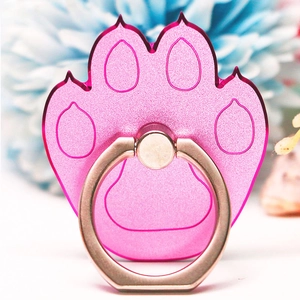 Macro shot of a pink cat paw metal phone ring holder with blurred floral background