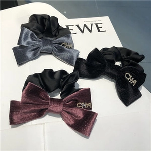 Détail de chouchous en satin tricolore avec lettres en métal serties de strass de style luxe
