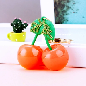 Creative cherry resin keychain with orange fruit, green leaves, and gold diamond accents