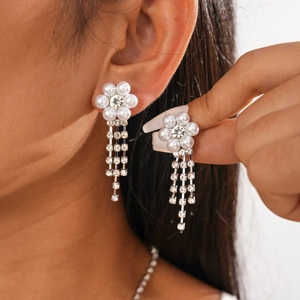 Detail shot of crystal flower earrings with long diamond-tassel pendants on a model