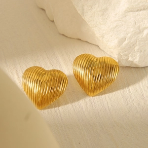 Detail shot of heart shaped gold stud earrings with elegant textured metal finish