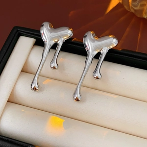 Macro detail of silver heart-shaped lava stud earrings in a premium jewelry box