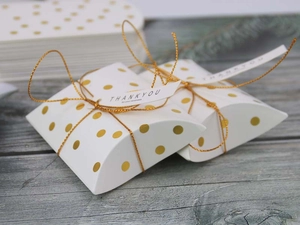 Macro view of white pillow candy box with gold polka dots and Thank You gift tag