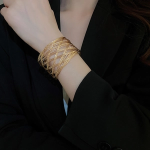 Close-up of golden layered woven mesh cuff bracelet on a model wearing black