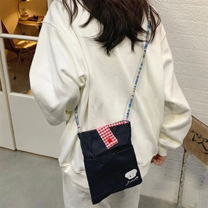 Back view of a cute embroidered dark denim crossbody bag with a red checkered strap