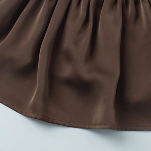 Detailed close-up of dark brown satin fabric with fine pleats and neat hem stitching