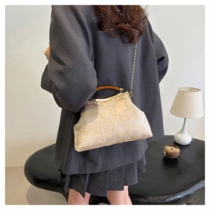 Classic cream embroidered kiss-lock handbag with amber handle shown on a model