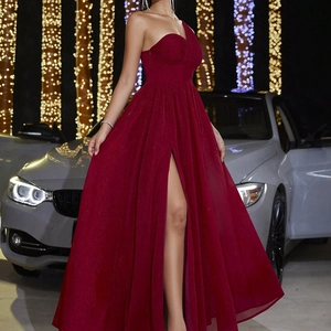 Detail of elegant deep burgundy one-shoulder gown with pleated fabric and high slit design