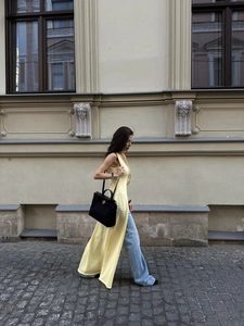 Yellow longline knit sleeveless cardigan with side slits paired with wide leg jeans