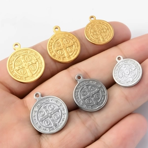 Saint Benedict medal pendants in gold and silver finish on hand with white background