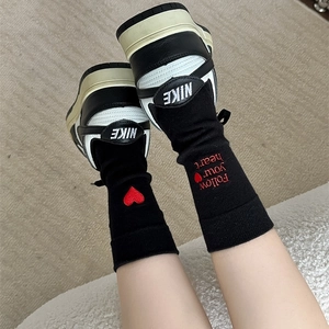 Detail of black cotton socks with red heart embroidery and Follow your heart text