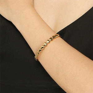 Detail of polished gold heart-shaped link bracelet with mirror finish on woman's wrist