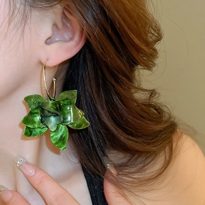 Close-up of a model wearing large green resin flower hoop earrings with gold metal rings