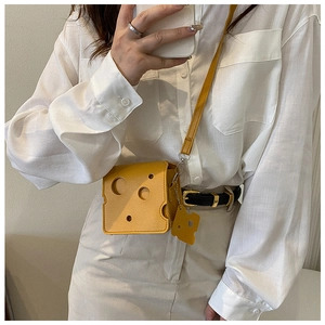 Creative yellow cheese shaped mini crossbody bag shown worn over a white shirt
