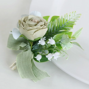 Sage green artificial wedding boutonniere with rose lily and ribbon on white plate