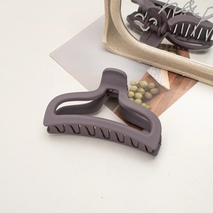 Detail view of large matte purple shark hair claw clip reflecting in a minimalist mirror