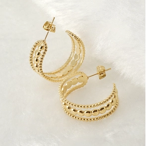 Détail macro de boucles d'oreilles C en or 18K avec triple couche de perles sur fond peluche