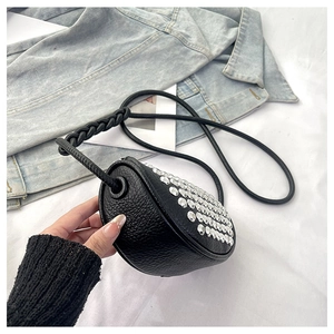 Detail of black pebbled leather crossbody bag with silver studs and braided strap