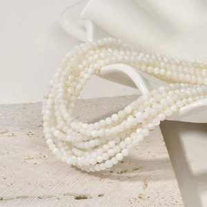 White 3mm natural freshwater shell round beads layered on a decorative stone plate